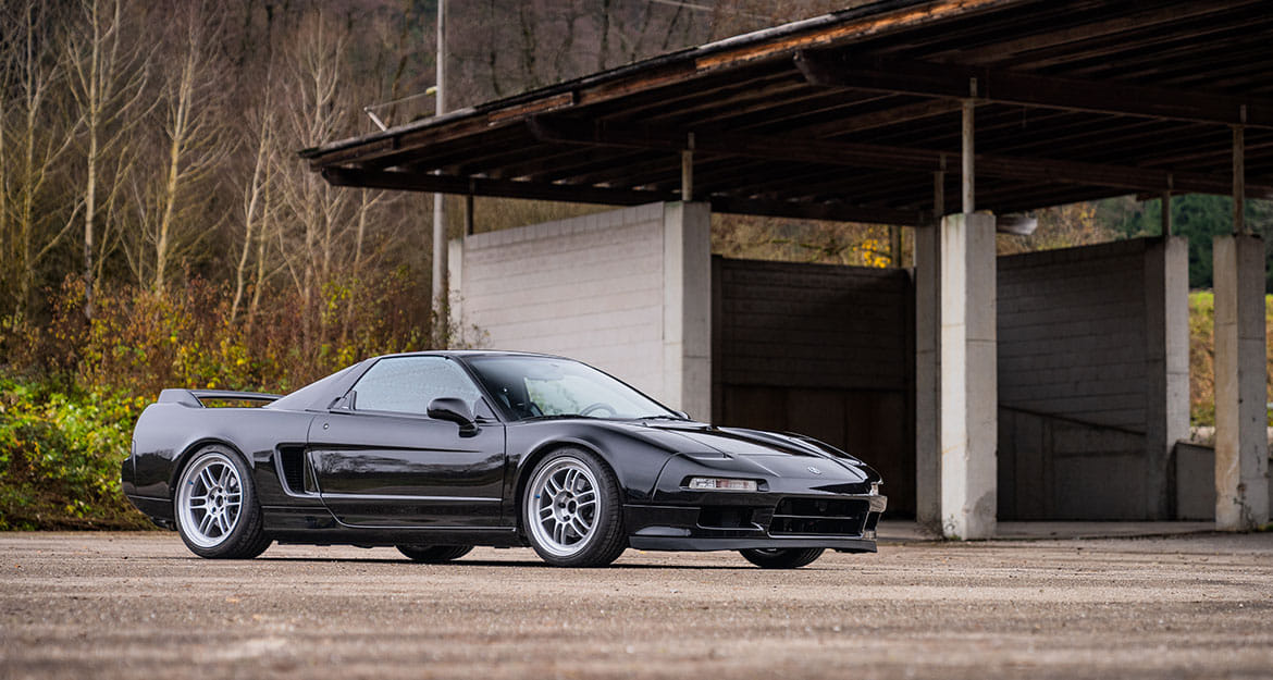 Lowered, black Honda NSX NA1 with KW coilover suspension on an industrial site