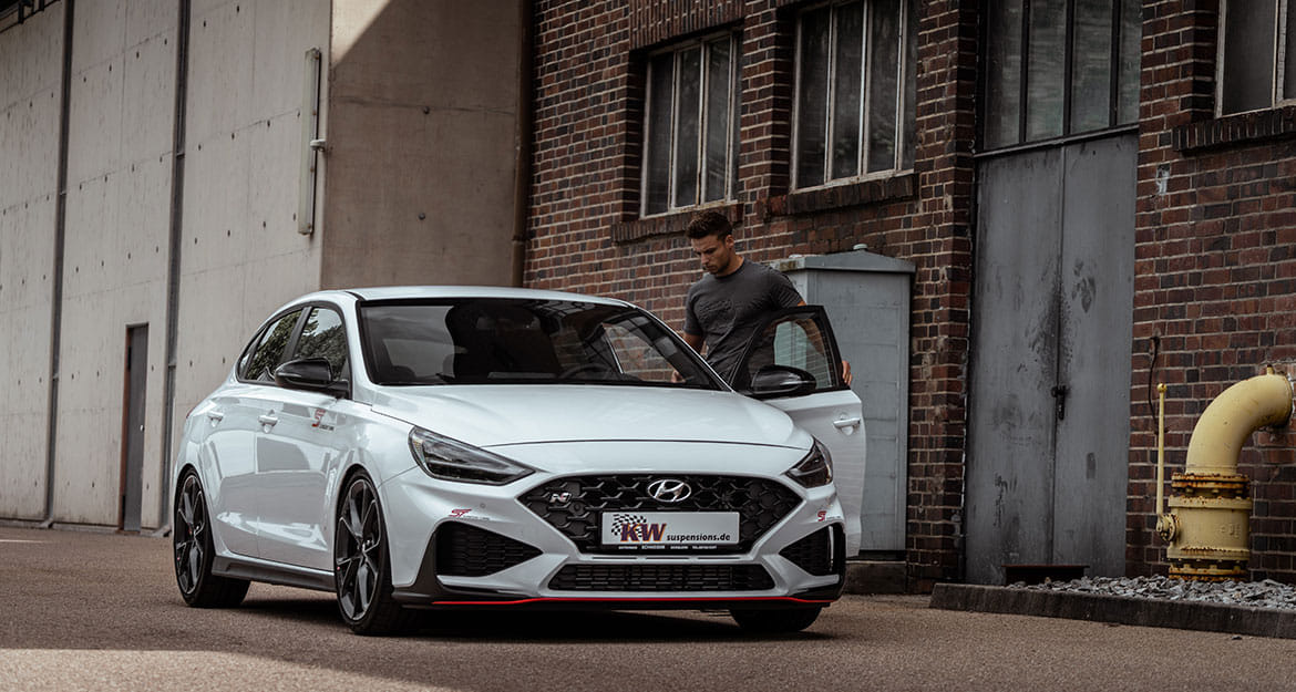 Young man gets into a white Hyundai i30 N equipped with KW V3 coilover suspension